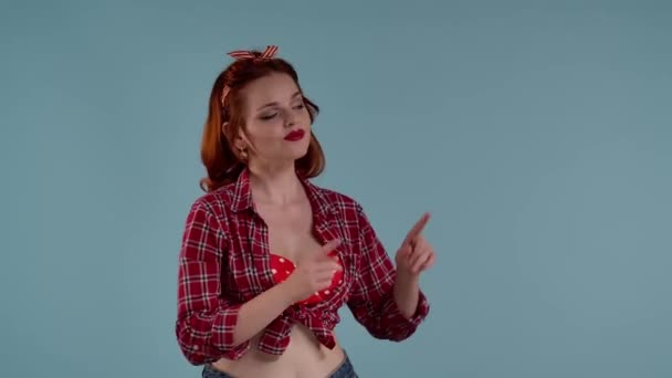 一个红头发 妆容鲜艳的年轻女孩站在蓝色背景的镜框里 把她的食指指向那个方向 这可能是你的广告 一个做广告的地方 — 图库视频影像