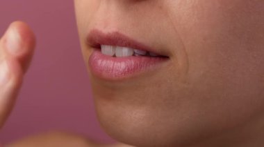 Deri dokusu ve güzellik konsepti. Çekici bir kadın modelin portresi. Yüzü makyajsız, ağzı açık genç bir kızın yakın plan fotoğrafı, parmaklarıyla dudaklarına dokunuyor.