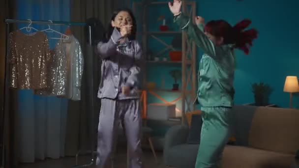 中完整的视频记录了两个年轻女子在一个房间里跳舞 听着一些充满活力的 充满活力的音乐 背景上挂着稀奇古怪的服装 女孩之夜 过夜者 兄弟姐妹 — 图库视频影像
