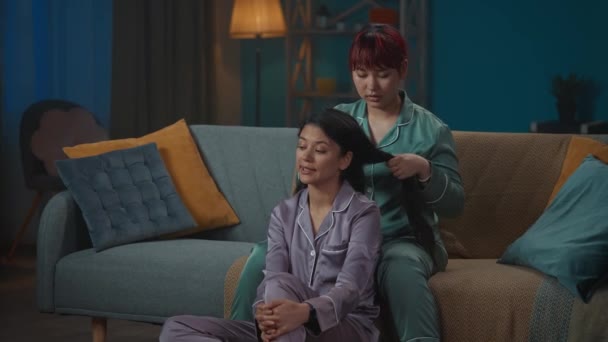 Pijamalı Iki Genç Kadının Kanepede Oturup Bir Şeyden Bahsederken Çekilmiş — Stok video