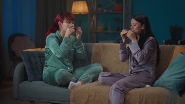 Średniej Jakości Filmik Jak Dwie Młode Kobiety Piżamie Siedzą Kanapie — Wideo stockowe