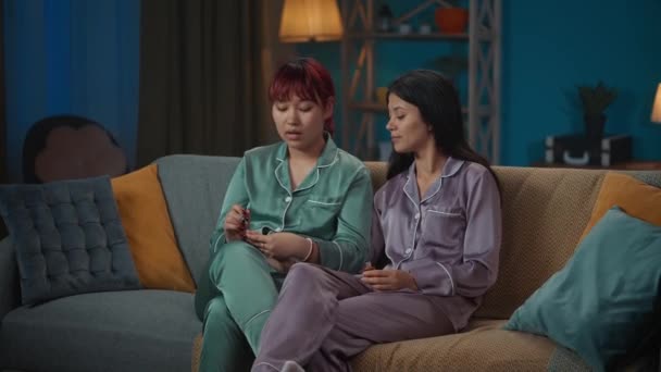 Średniej Jakości Filmik Którym Dwie Młode Kobiety Piżamie Siedzą Kanapie — Wideo stockowe