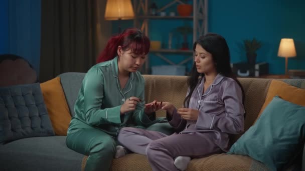 Medelstor Video Där Två Unga Kvinnor Pyjamas Sitter Soffan Ett — Stockvideo