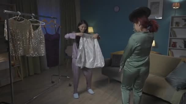 全尺寸的视频记录了两个年轻女子在一个房间里跳着充满活力的音乐 她们在衣架上试穿不同的服装和配饰 女孩之夜 过夜者 — 图库视频影像