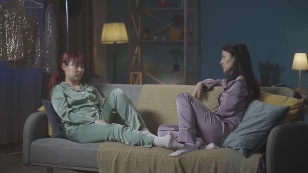 全长视频记录了两个穿着睡衣的年轻女人坐在房间沙发上 分享秘密 谈论什么 女孩之夜 过夜者 兄弟姐妹 — 图库视频影像