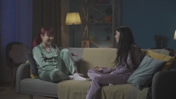 全长视频记录了两个穿着睡衣坐在房间沙发上的年轻女性 她们分享秘密 谈论什么和大笑 女孩之夜 过夜者 — 图库视频影像