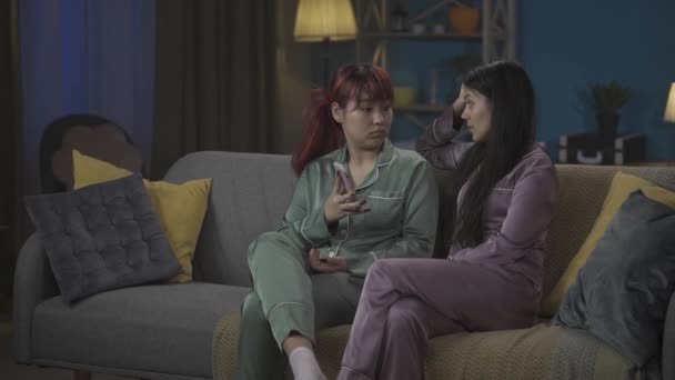 中完整的视频记录了两个年轻女子坐在沙发上的情景 其中一个人很伤心 她的朋友 姐姐都想让她高兴起来 兄弟姐妹 心血来潮 精神支持 — 图库视频影像