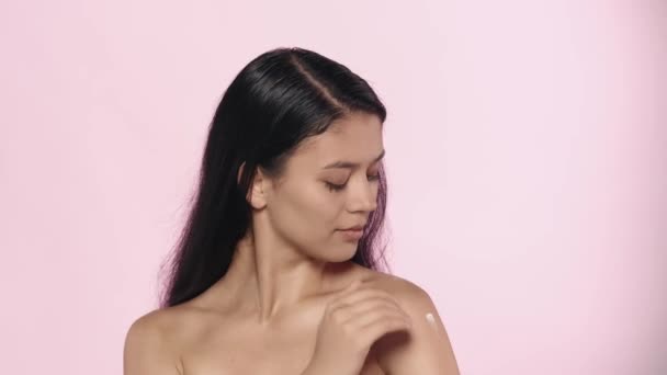 美容美发广告的概念 服装工作室拍摄美丽的女模特 裸体的布鲁内特女孩 在肩膀光滑的皮肤上涂上护肤霜 — 图库视频影像