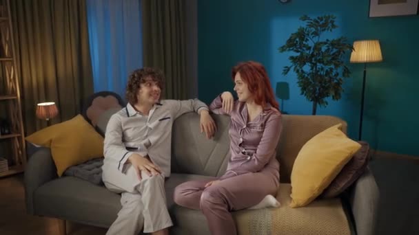 家族と人間関係の広告コンセプト 一緒に過ごした若いカップルの肖像画 ソファーに座って話し 枕の戦いを始めるパジャマの男女 疲れた笑い — ストック動画