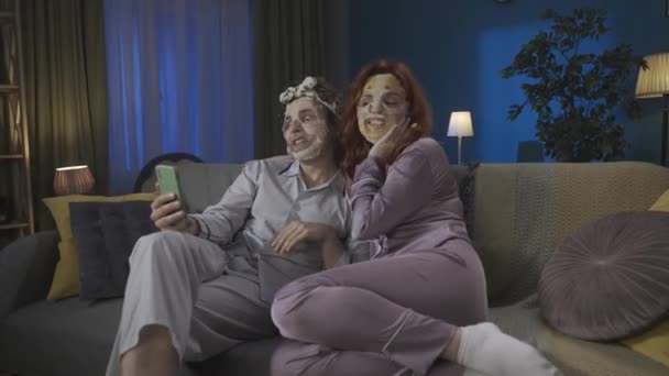 家庭和关系广告概念 一对年轻夫妇在一起度过时光的画像 男人和女人坐在沙发上 戴着面具 用智能手机通过视频通话 Hdr — 图库视频影像