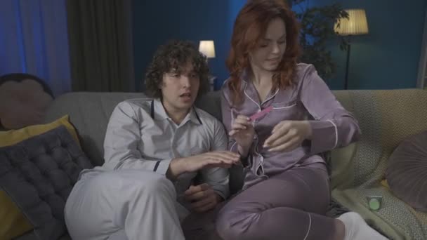 家族と人間関係の広告コンセプト 一緒に過ごした若いカップルの肖像画 ソファーの上のパジャマの男女 女性は ハンドクリームでマッサージを行います Hdrについて — ストック動画