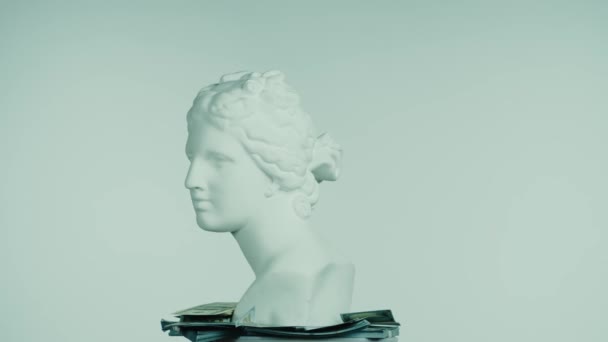 美丽的古代女神维纳斯大理石雕像的合影照片 周围都是钱 罗马时代女性半身像的肖像在平台上旋转 被蓝色背景隔离了富有创意的抽象概念 — 图库视频影像
