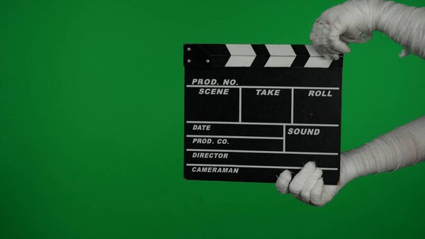 Detail green screen isolated chroma key photo capturing mummys hands holding a directors film movie slateboard, clapper board. Mock up, workspace for your promotion clip or advertisement.