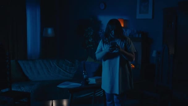 若い女性がアパートを興奮させ 超常的な活動に気づき 部屋の明かりを点滅させるビデオでズーム 彼女は誰かに助けを求めている ハンティングされた家 超自然的な — ストック動画