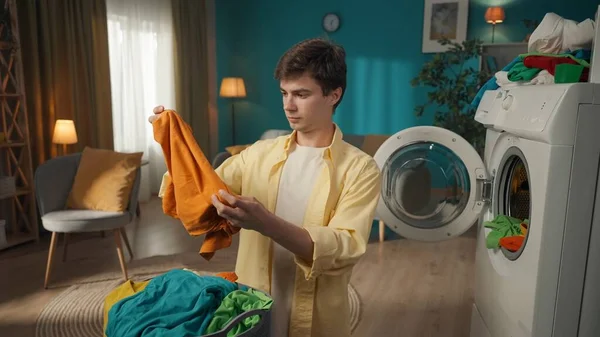 中全垒打 深色头发的男人从洗衣机里卸下洗好的衣服 检查衣服上是否留有污迹 家用电器 家务活 促销和广告 — 图库照片