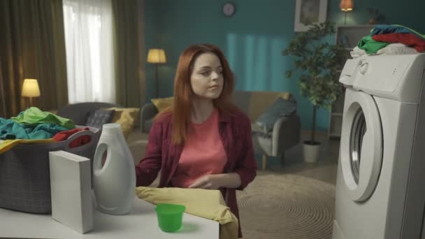 Kızıl Saçlı Kadın Çamaşır Makinesinin Yanında Oturuyor Bir Bardağa Sıvı — Stok video