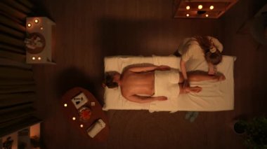 Vücut bakımı reklam konsepti. Güzellik ameliyatı olan kadın portresi. Spa salonunun en iyi manzarası, masaj masasındaki kadın, terapist ayakları üzerinde uzanıyor, bacaklarını kaldırıyor. Yavaş çekim