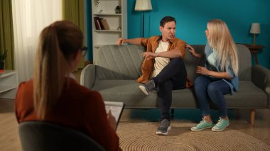 Yıkılmış evlilik ve terapi. Bir kadın agresif ve sinirli bir adamı sakinleştirmeye çalışır. Evli bir çift, kadın bir terapistin önünde kanepede oturuyor. Aile krizi, evlilik danışmanlığı konsepti