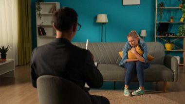 Erkek bir psikolog depresyondan muzdarip mutsuz bir kadınla çalışıyor. Kadın, uzmanın önünde kanepede oturur ve yastığa sarılır. Psikoterapi seansına katılacağım.