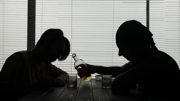 ショットは 施設に座っている2人の若者 カフェを示しています 一人はグラスにアルコールを注いでいる 彼らは社会化し 中毒を示しています アルコール依存症 対話者 ミディアムビデオ — ストック写真