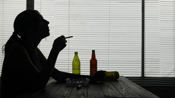 Frame Young Woman Sits Table Surrounded Empty Bottles She Demonstrates — Stock Photo, Image