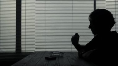 Çerçevede, bir enstitüde, bir kafede genç bir adam oturuyor. Sigara içiyor, yanında da kül tablası var. Nikotine olan bağımlılığını gösteriyor. Yalnız ve üzgün..