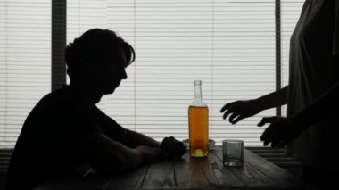 Çerçevede, bir enstitüde, bir kafede oturan genç bir adam var. Garson ve bardaktan bir şişe alkol almış. Tek başına içecekmiş. Alkol bağımlılığı, üzüntü.