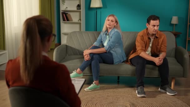 憤慨した女性は カウンセリングセッションで配偶者の欠点を挙げます カウンセラーのオフィスでソファーに座っている夫婦 セラピー カウンセリング心理学者 — ストック動画