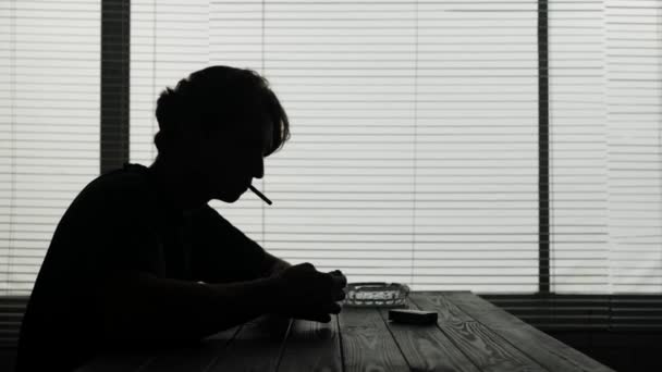 若い男がカフェに座っている 彼はイライラしている 悲しい その後 タバコを点灯させ 咳を始める 彼は気に入らないが タバコを吸っている ニコチン中毒を示しています — ストック動画