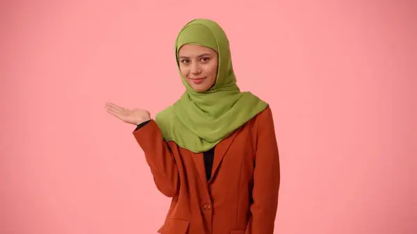 中等尺寸的孤立的照片拍摄的是一个戴着头巾 头戴面纱的年轻貌美女子 她把她的手指向镜框的左边 你的广告 促销的地方 — 图库照片