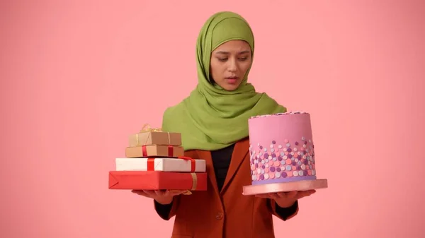 中等尺寸的孤立的照片拍摄的是一个戴着头巾 头戴面纱的年轻貌美女子 她手里拿着礼物和蛋糕 很沮丧 你的广告 多样性的地方 — 图库照片