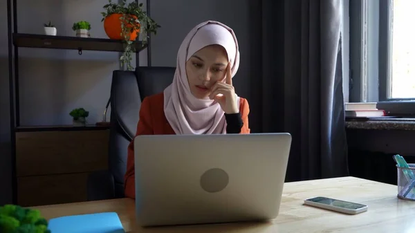 中等尺寸的照片拍摄的是一个戴着头巾 头戴头巾的年轻貌美女子 她在笔记本电脑上工作或学习 思考着什么 文化多样性 就业和教育 — 图库照片