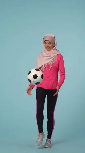 スポーツウェアとヒジャーブ シーラを着た魅力的な若い女性を撮影するフルサイズの孤立した写真 彼女はボールを追い払っている モックアップ プロモーション スポーツのための場所 — ストック写真