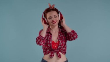 Mavi arka plandaki resimde, parlak makyajlı genç bir kadın. Kablosuz kırmızı kulaklık takıyor. Şarkı söyler ve dans eder. Şarkıyı seviyor ve seviyor, şarkıyı. Orta boy video.