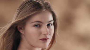 Üç renkli arka planda, uzun beyaz saçlı, güzel bir kadının yakın plan çekiminde. O, saçını yana doğru kamçılıyor. Kameraya bakar ve gülümser. Yavaş çekim.