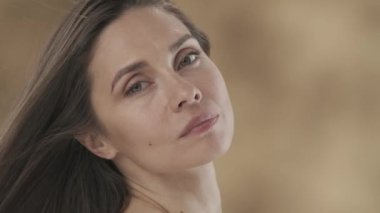 Çerçevede orta yaşlı bir kadın var. O yan yana duruyor, yana bakıyor. Yavaşça başını çevirir, kameraya bakar ve gülümser. Rüzgar saçlarını savuruyor. Yavaş çekim