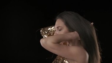 Siyah arka planda orta yaşlı, siyah saçlı bir kadın var. Yana doğru duruyor ve rüzgar saçlarını savururken uzaklığa bakıyor. Sonra kameraya bakmak için döndü ve gülümsedi. HDR BT2020