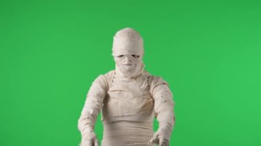 Yeşil ekran izole edilmiş kroma anahtar video mumyayı kollarını sallarken, sanki cesaretlendiriyormuş gibi, sizi katılmaya çağırıyor. Cadılar Bayramı. Model yapın, tanıtımınız veya reklamınız için çalışma alanı.