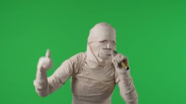 Yeşil ekran, bir mumyanın dans edişini ve mikrofona şarkı söyleyişini gösteren krom anahtar videoyu izole etti. Cadılar bayramı. Model yapın, tanıtım videonuz ya da reklamınız için çalışma alanı.