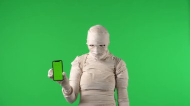 Yeşil ekran, reklam alanı olan akıllı bir telefonu tutan tüyler ürpertici bir mumyanın videosunu izole etti. Çalışma alanı, tanıtım videonuz ya da ürün reklamınız için model oluşturdu. Cadılar Bayramı.