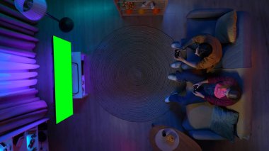 Oyun ve eğlence reklam konsepti. Çift kanepede oturuyor TV 'de video oyunu oynuyor Chroma anahtar yeşil ekran, reklam alanı çalışma alanı modeli.