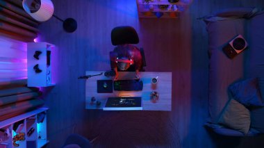 Çevrimiçi oyun reklam konsepti. Evde modern bilgisayar olan bir oda manzarası. Kulaklıklı bir kızın internette oyun oynaması, abur cubur yemesi, kahve içmesi..