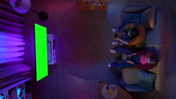 网络游戏和流媒体广告的概念 一对夫妻坐在房间的沙发上 用Chroma键绿色屏幕在电视上丢失视频游戏 广告区工作区模拟的头像 — 图库视频影像
