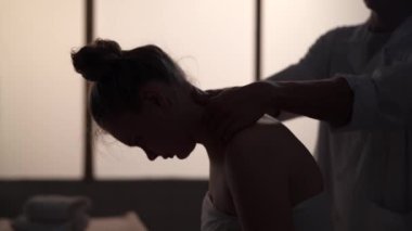Yakın plan. Masör, masaj uzmanı hastasına boyun masajı yapıyor. Masaj odasında bir kadınla bir erkeğin siluetleri, spa prosedürü. Sağlık, tıbbi tedavi, bütünsel terapi.