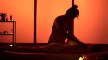 Masör, masaj uzmanı hastasına sırt masajı yapıyor. Masaj odasında siluetler, spa prosedürü. Egzotik, turuncu neon ışıklar. Sağlık, tıbbi tedavi, bütünsel terapi.