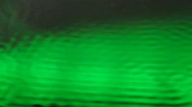 Su ve ses yaratıcı soyut bir kavram. Su yüzeyinin yakın çekim stüdyosu. Güzel yeşil neon ışığı olan su, ultra ses titreşimleri altında dalgalanmalar yaratıyor, soyut arka plan şablonu.