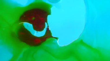 Su ve sıvı, yaratıcı ve soyut kavramları karıştırıyor. Stüdyonun su yüzeyini kapatın. Yeşil renkli mürekkep yüzeyi, rüzgarla esen kırmızı yağ damlası, soyut arka plan. Yavaş çekim.