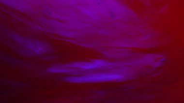 Su ve sıvı, yaratıcı ve soyut kavramları karıştırıyor. Stüdyonun su yüzeyini kapatın. Neon altında şeffaf suda hareket eden canlı kırmızı ve mavi mürekkep, soyut arkaplan. Yavaş çekim.