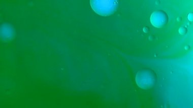 Su ve sıvı, yaratıcı ve soyut kavramları karıştırıyor. Su yüzeyinin yakın çekim stüdyosu. Açık yeşil mürekkep renkli su ve yağlı damlalar yüzeyde akıyor, soyut bir zemin. Yavaş çekim.