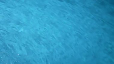 Su ve ışık yaratıcı reklam konsepti. Su yüzeyinin yakın çekim stüdyosu. Güzel mavi şeffaf su yüzeyi akarsu gibi hızlı akıyor ve daireler ve dalgalar oluşturuyor. Yavaş çekim.